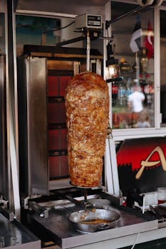 Close-up of succulent shawarma meat roasting on a vertical rotisserie in a restaurant setting.