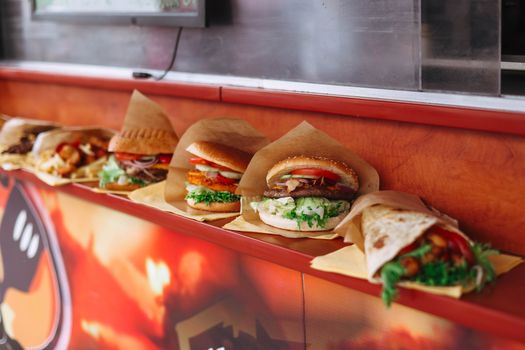 Selection of assorted fast food items like burgers and wraps on a restaurant counter.