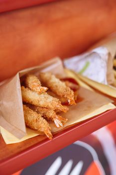 Golden fried shrimp in a paper cone, perfect for a delicious snack or meal.
