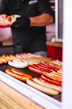 A street food vendor prepares mouthwatering grilled sausages at a market.
