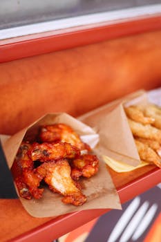 Crispy hot chicken wings served with fries in paper boats, great for a tasty meal.