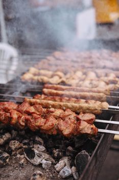 Appetizing meat skewers grilling on a charcoal barbecue with smoke rising outdoors.
