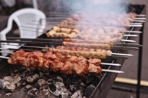 Free Juicy skewered meat grilling on open flame barbecue outdoors, perfect for dinner party. Stock Photo