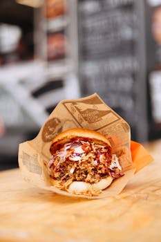 Appetizing close-up of a pulled pork sandwich with coleslaw, wrapped in paper.