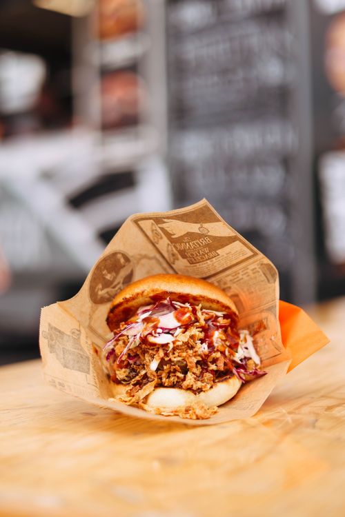 Free Appetizing close-up of a pulled pork sandwich with coleslaw, wrapped in paper. Stock Photo