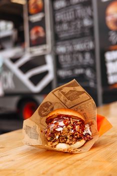 Delicious pulled pork sandwich wrapped in paper at a food truck. Perfect for a quick tasty bite.