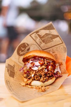 Delicious gourmet burger with crispy onions and coleslaw, wrapped in vintage paper, perfect for street food lovers.
