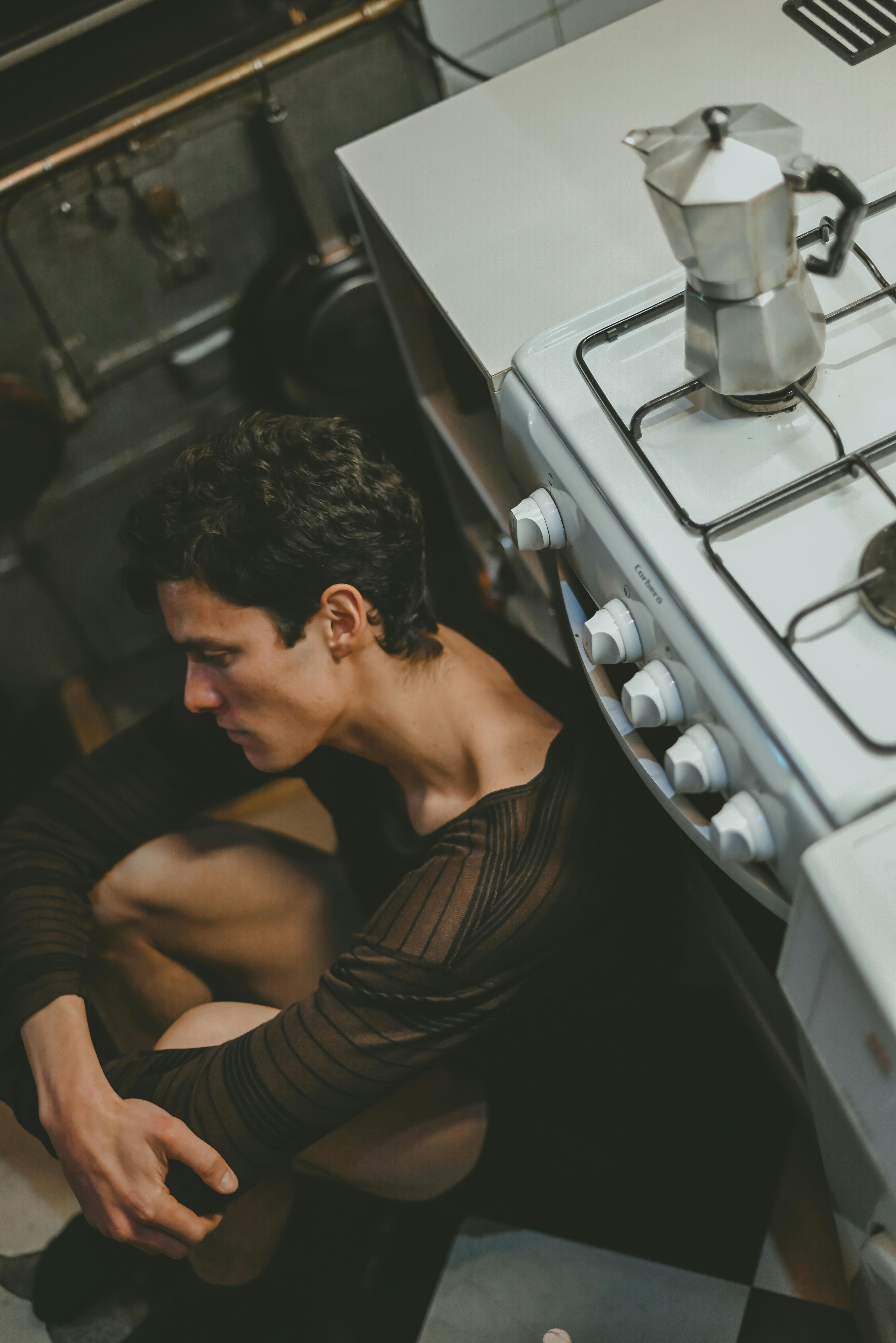 a man sitting on the floor next to a stove