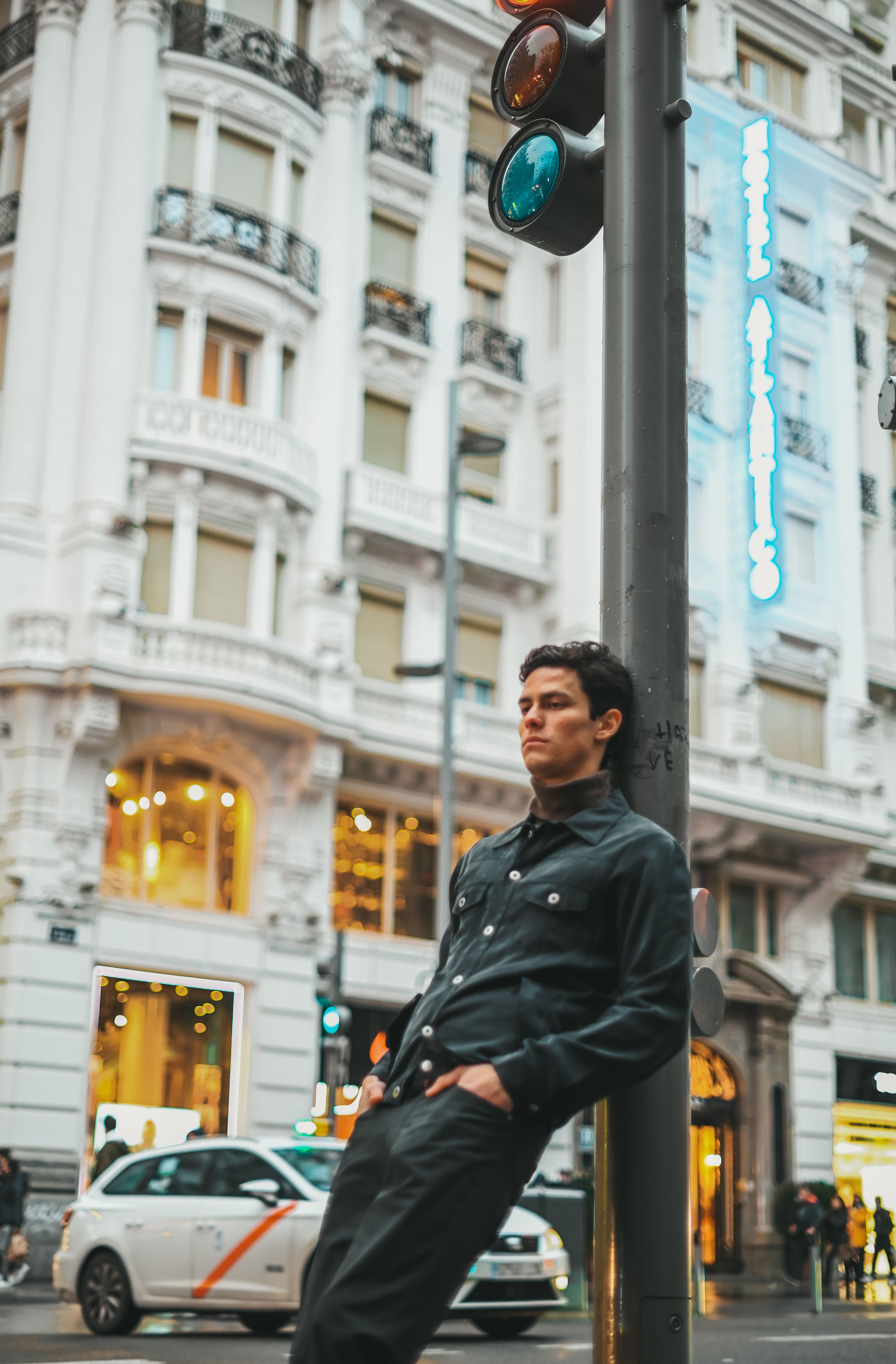A man leaning against a traffic light · Free Stock Photo