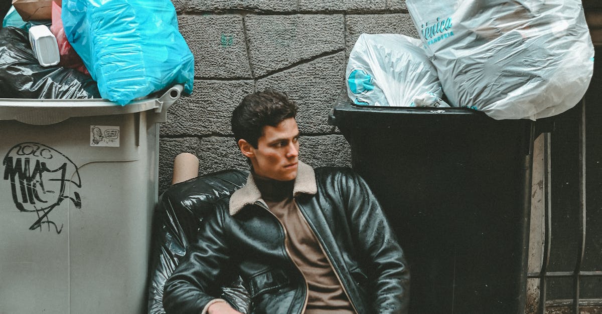 A man sitting on the curb next to a trash can