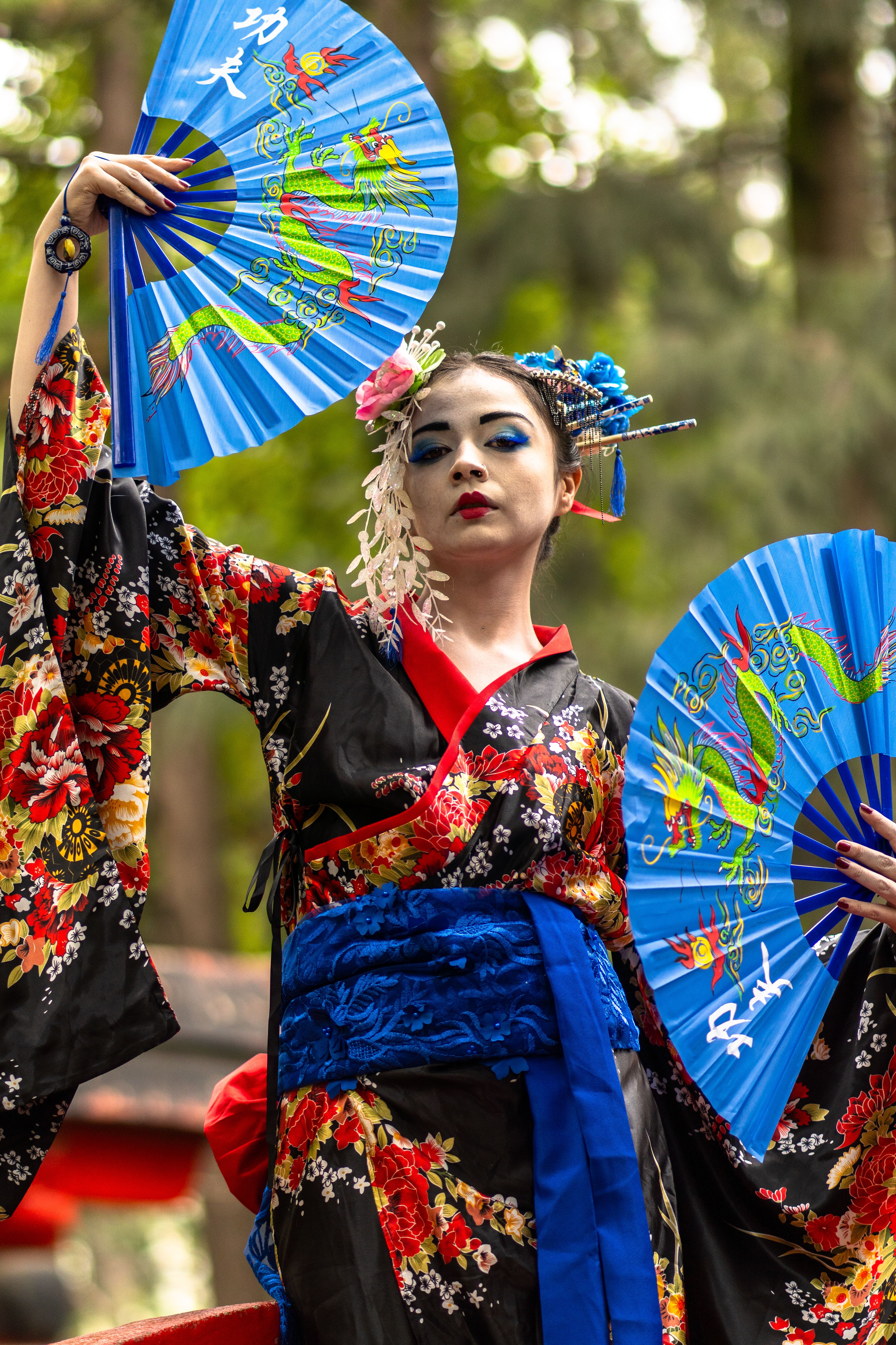 A woman in a geisha costume holding two blue fans · Free Stock Photo