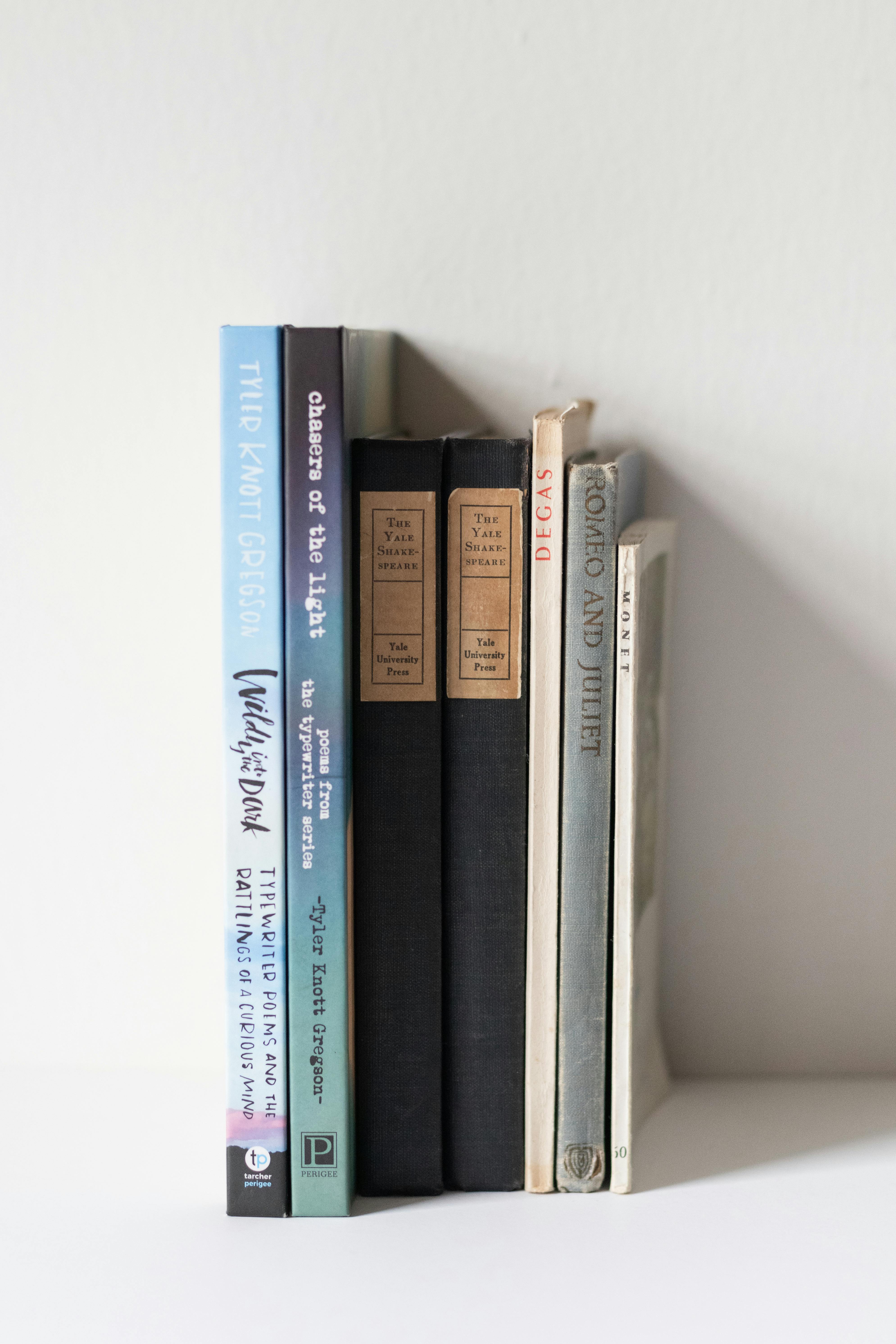 a stack of books on a shelf with a white wall