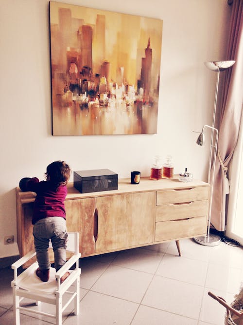 Free Toddler Standing on White Chair Beside Sideboard Stock Photo
