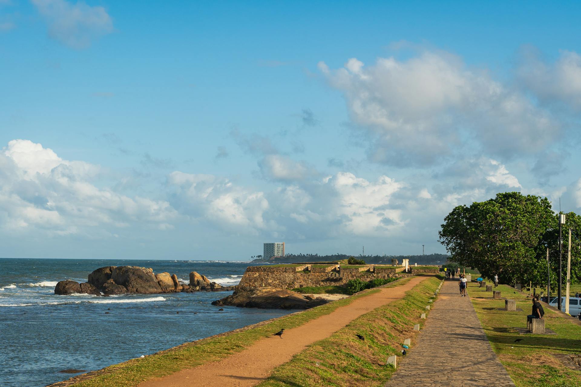 Explore the scenic seaside pathway at Galle Fort in Sri Lanka, capturing ocean waves and lush greenery.