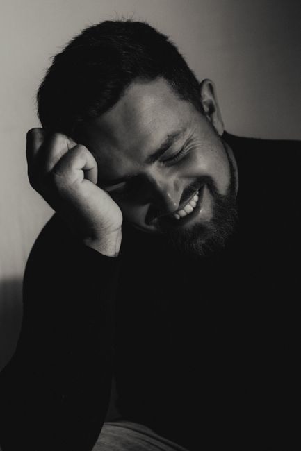 Artistic black and white side profile portrait of a smiling young man in a thoughtful pose.