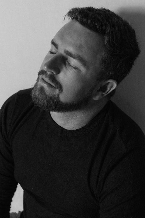 Free A contemplative black and white portrait of a man with a beard in a studio setting. Stock Photo