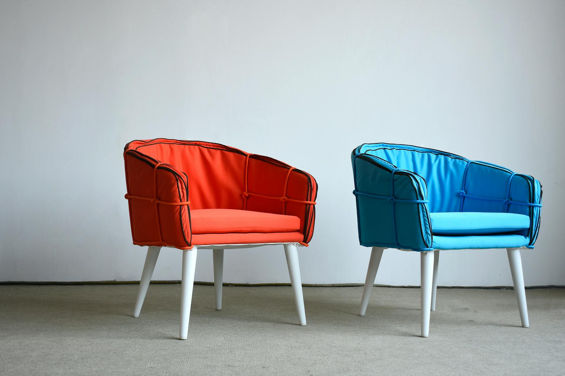 Modern orange and blue chairs against a minimalist background, showcasing unique design.