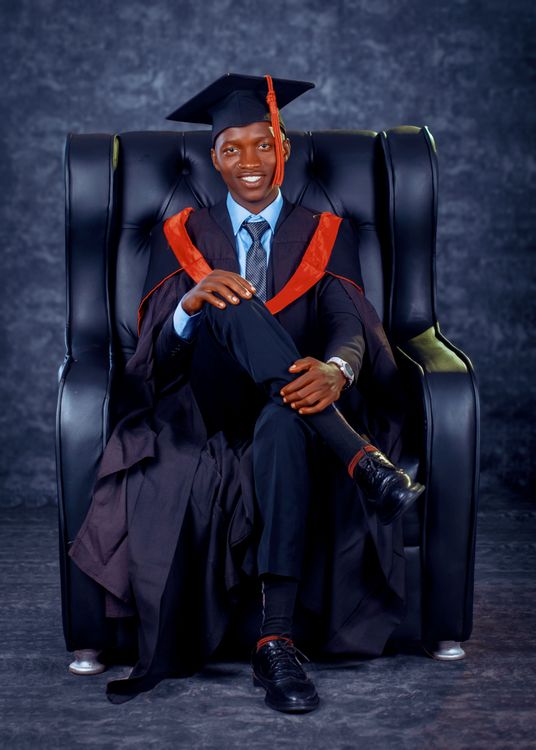 A man in a graduation gown sitting in a chair Free Stock Photo A man in a graduation gown sitting in a chair Free Stock Photo