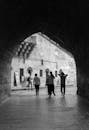 A black and white photo of people walking through an archway
