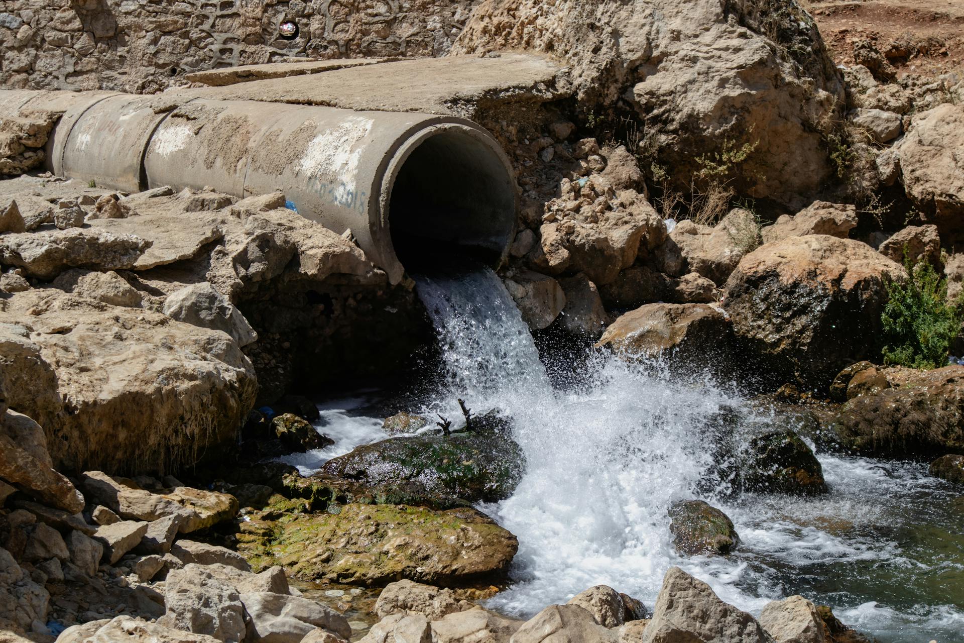 Vibrant water flow through a large pipe in the rocky landscape of Sinek, Diyarbakır.