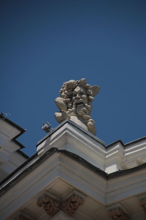 Free Close-up of a detailed sculpture on a classic building facade under bright blue skies. Stock Photo