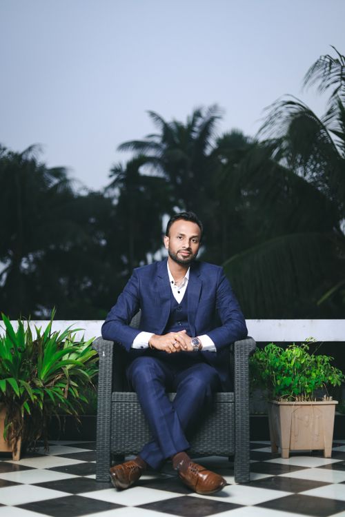 Free Well-dressed man in a blue suit sitting outdoors, surrounded by plants Stock Photo