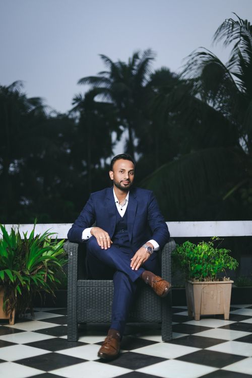 Free Man in formal attire seated outdoors on a patterned floor with plants. Stock Photo