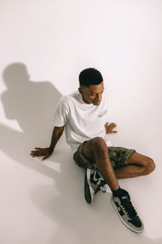 Young adult in relaxed pose wearing casual urban fashion indoors with natural shadow.