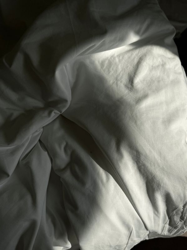 Soft folds of white bedding in low sun — Tetiana Androshchuk on Pexels