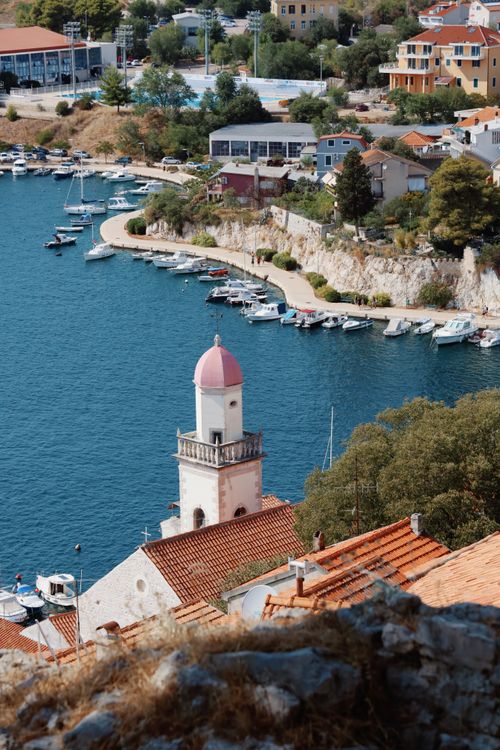 Free Picturesque view of a coastal town with harbor, church tower, and boats along the Adriatic Sea. Stock Photo
