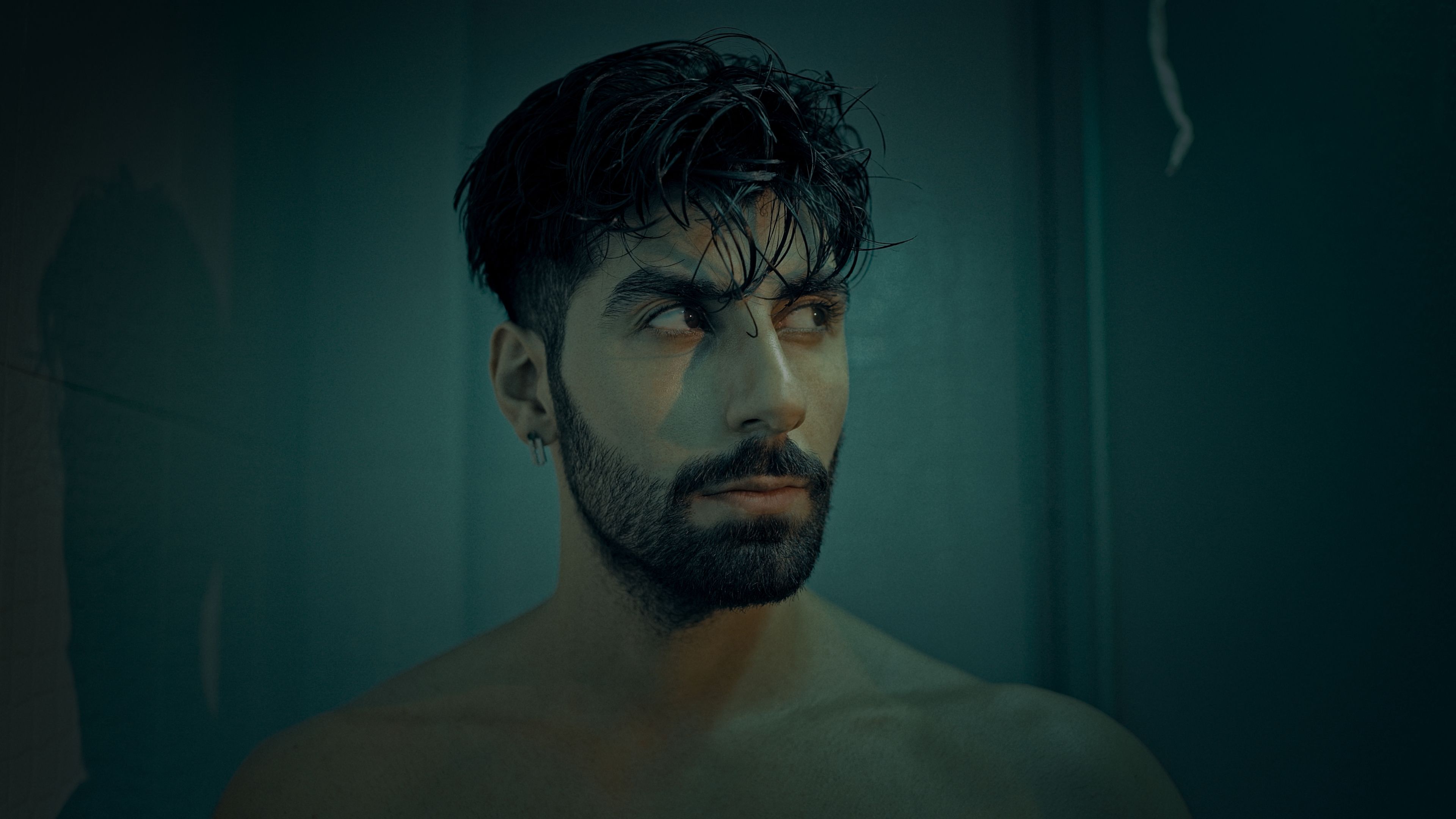 イスタンブールの暗いスタジオセッティングで、ひげを生やした大人の男性の芸術的なポートレート。