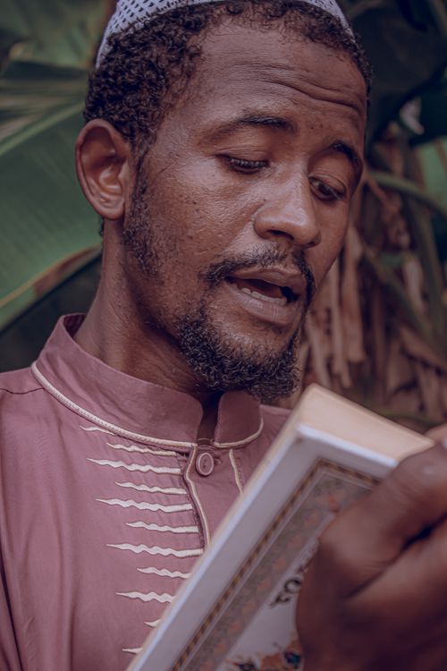 Free Man in traditional clothing reading a book outdoors, showcasing cultural expression. Stock Photo