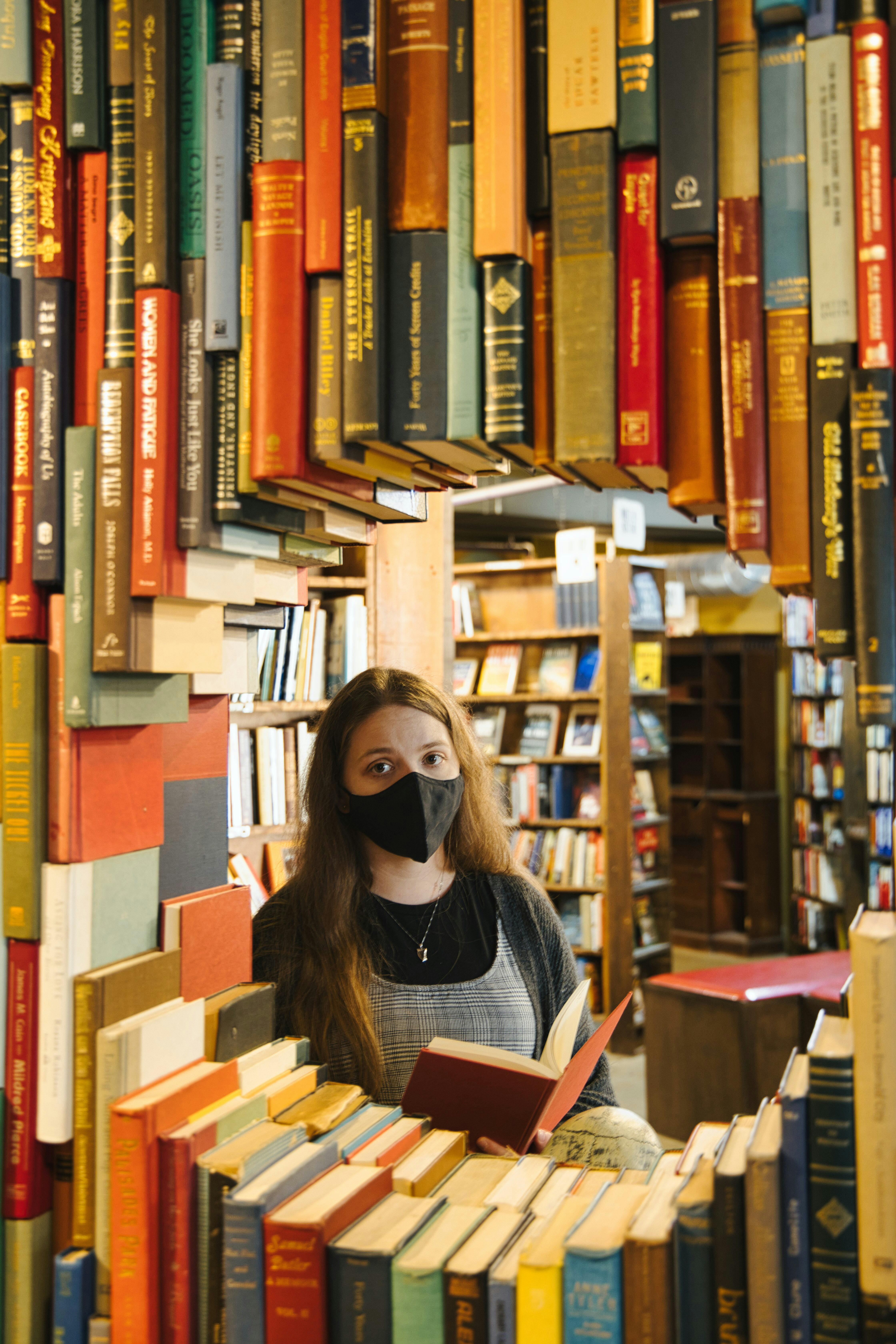 a woman wearing a mask is reading a book