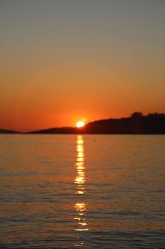 A picturesque sunset casting vibrant reflections over the tranquil ocean surface.