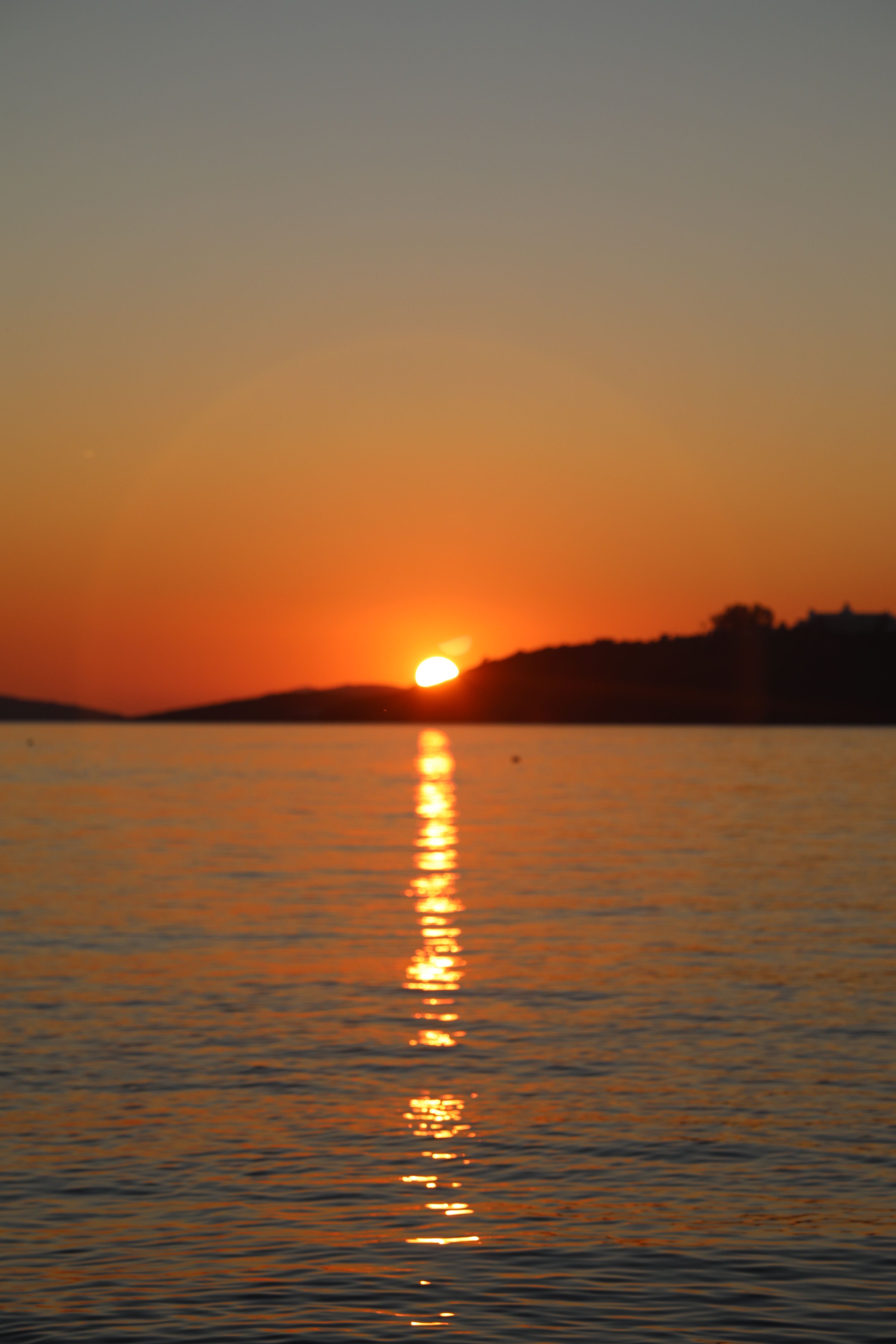 A sunset over the water with a boat in the foreground · Free Stock Photo