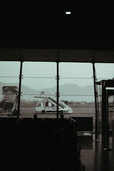 Moody airport scene with silhouetted lounge and view of runway stairs.