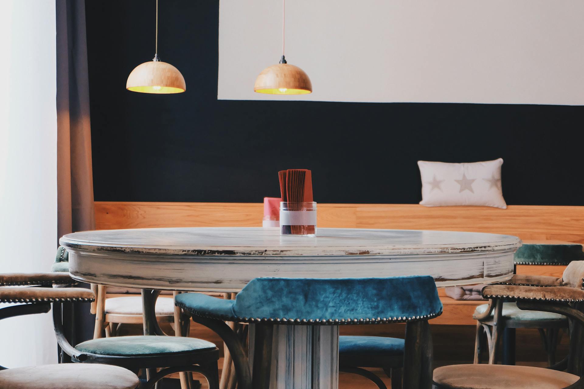 A stylish café interior featuring vintage wooden furniture and contemporary lighting.