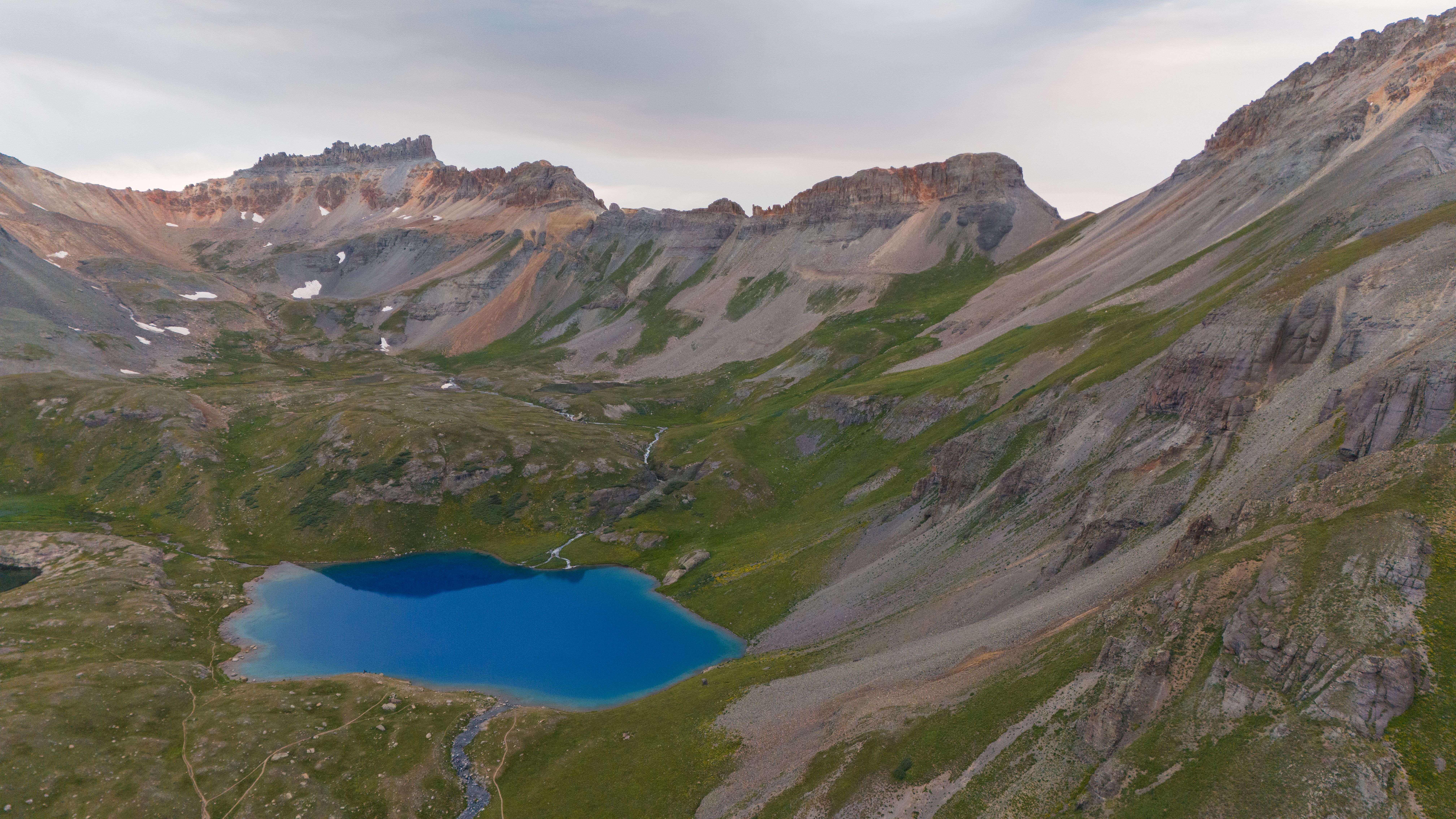 A mountain lake surrounded by mountains and grass · Free Stock Photo