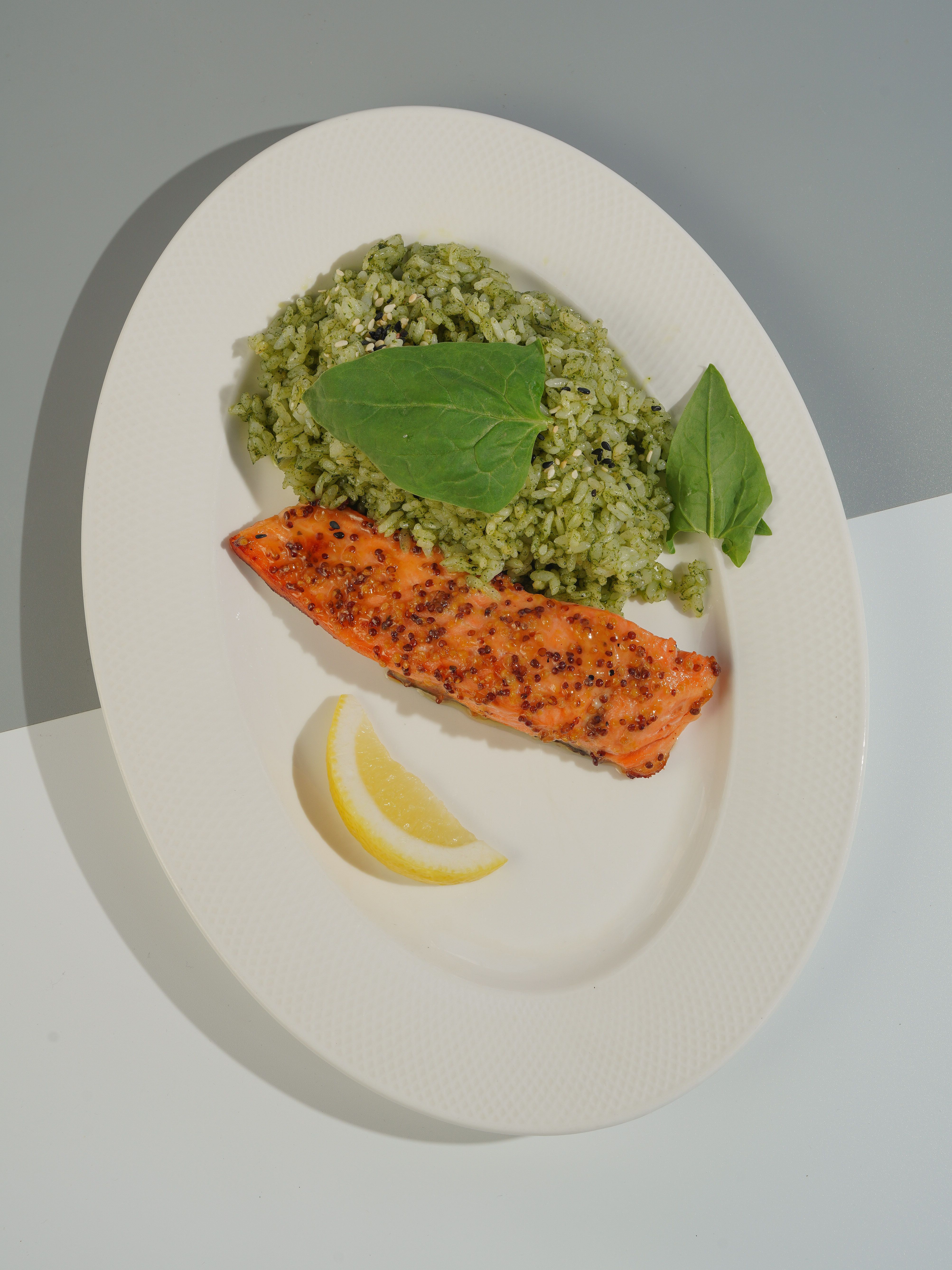 Delicious grilled salmon with spinach risotto, garnished with fresh spinach and lemon slices.