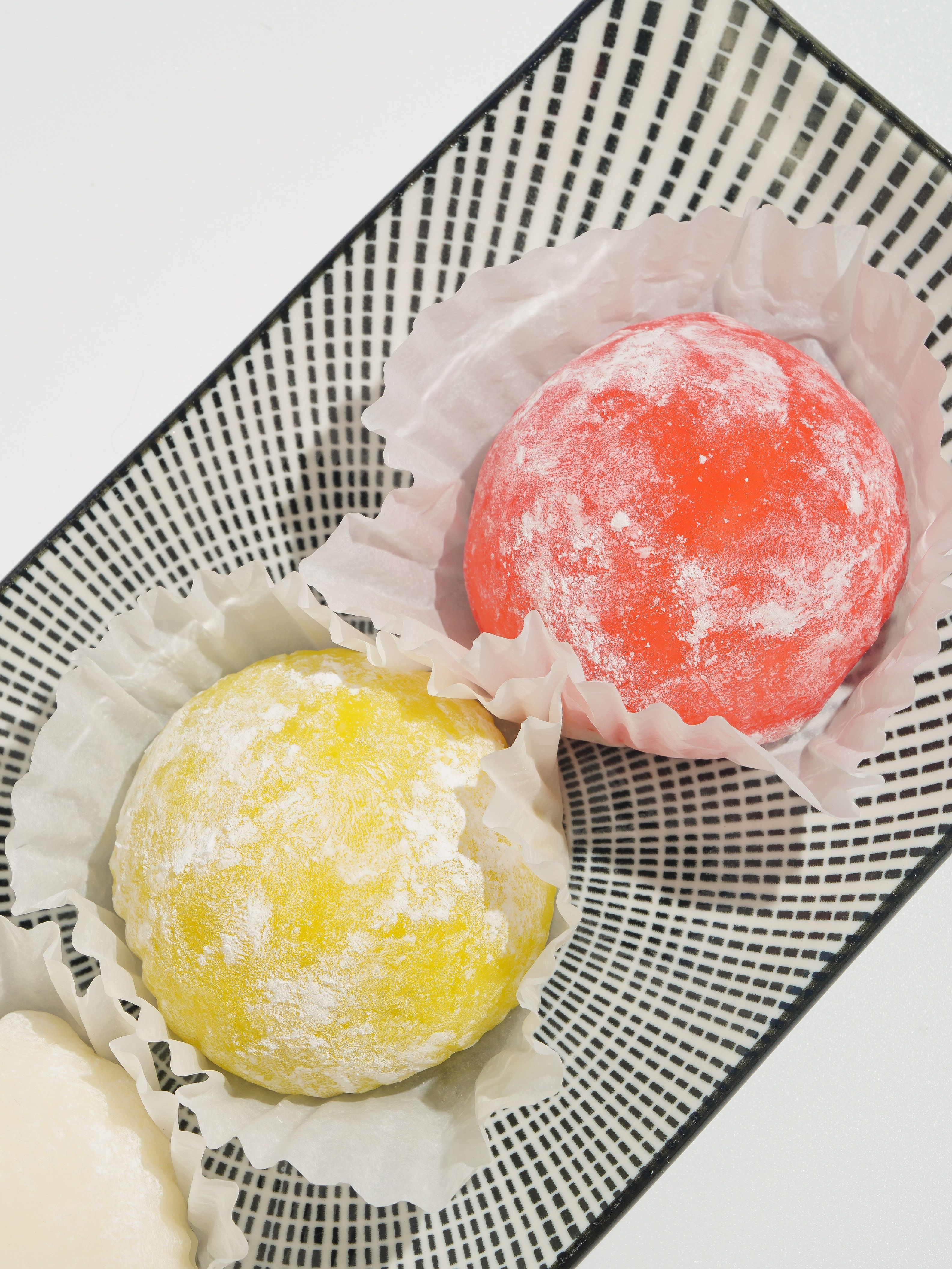 Vibrant yellow and red mochi ice cream delicately placed in a stylish plate.