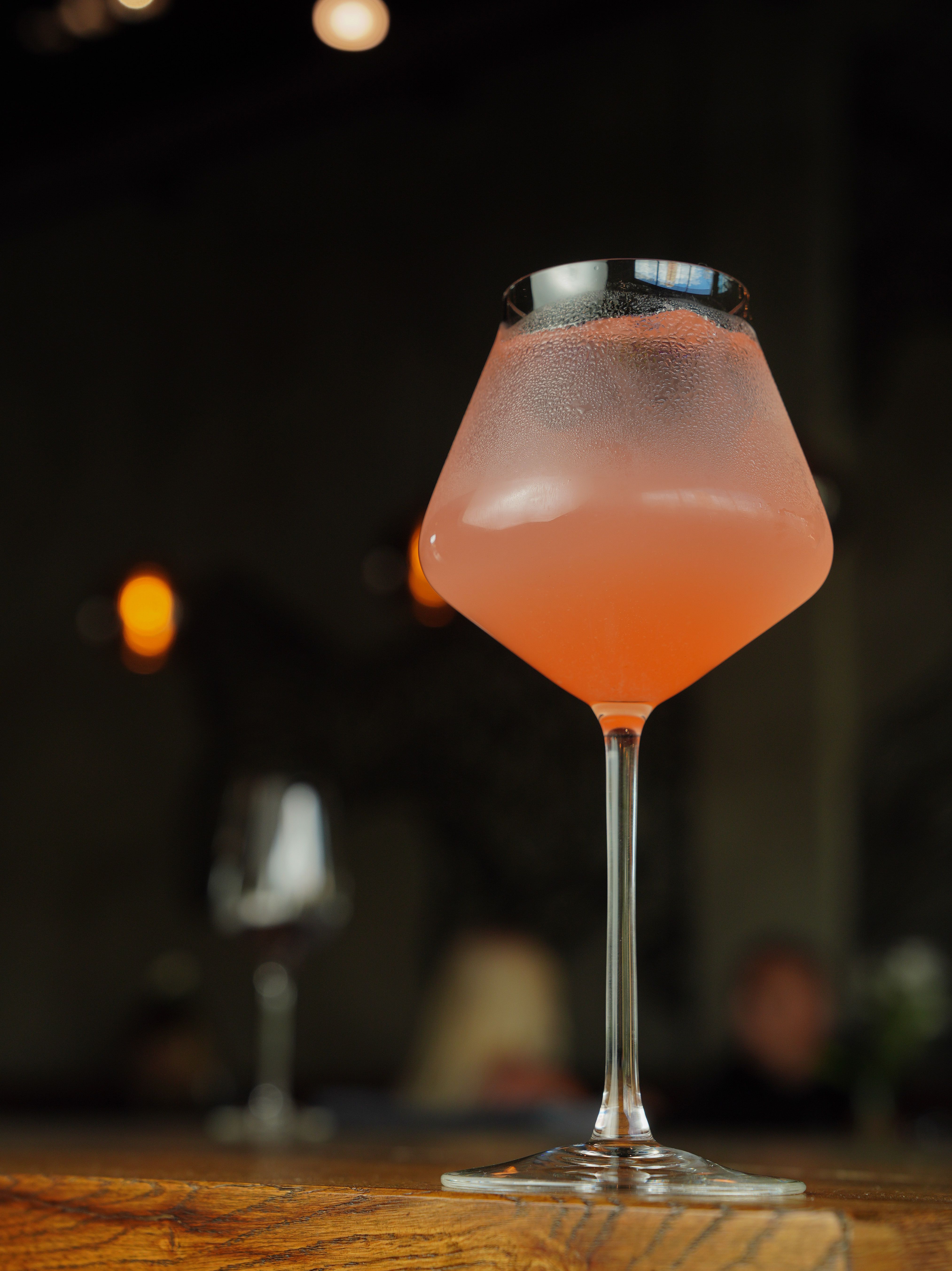 A pink cocktail sitting on top of a wooden table · Free Stock Photo