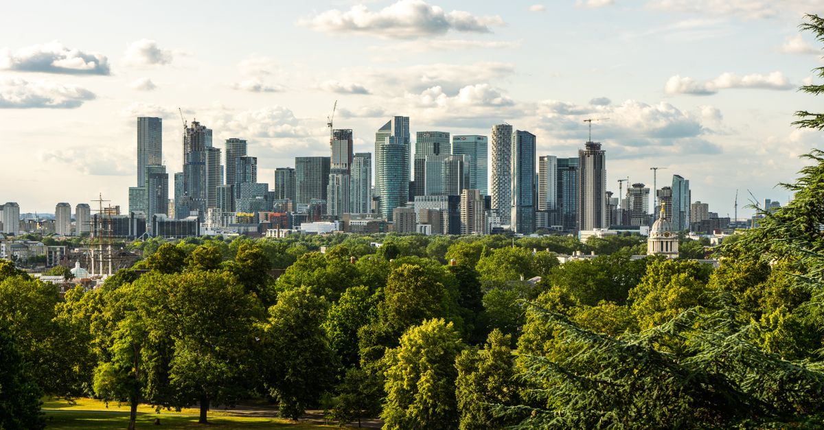Panoramic view of London's Canary Wharf skyline from lush Greenwich Park.