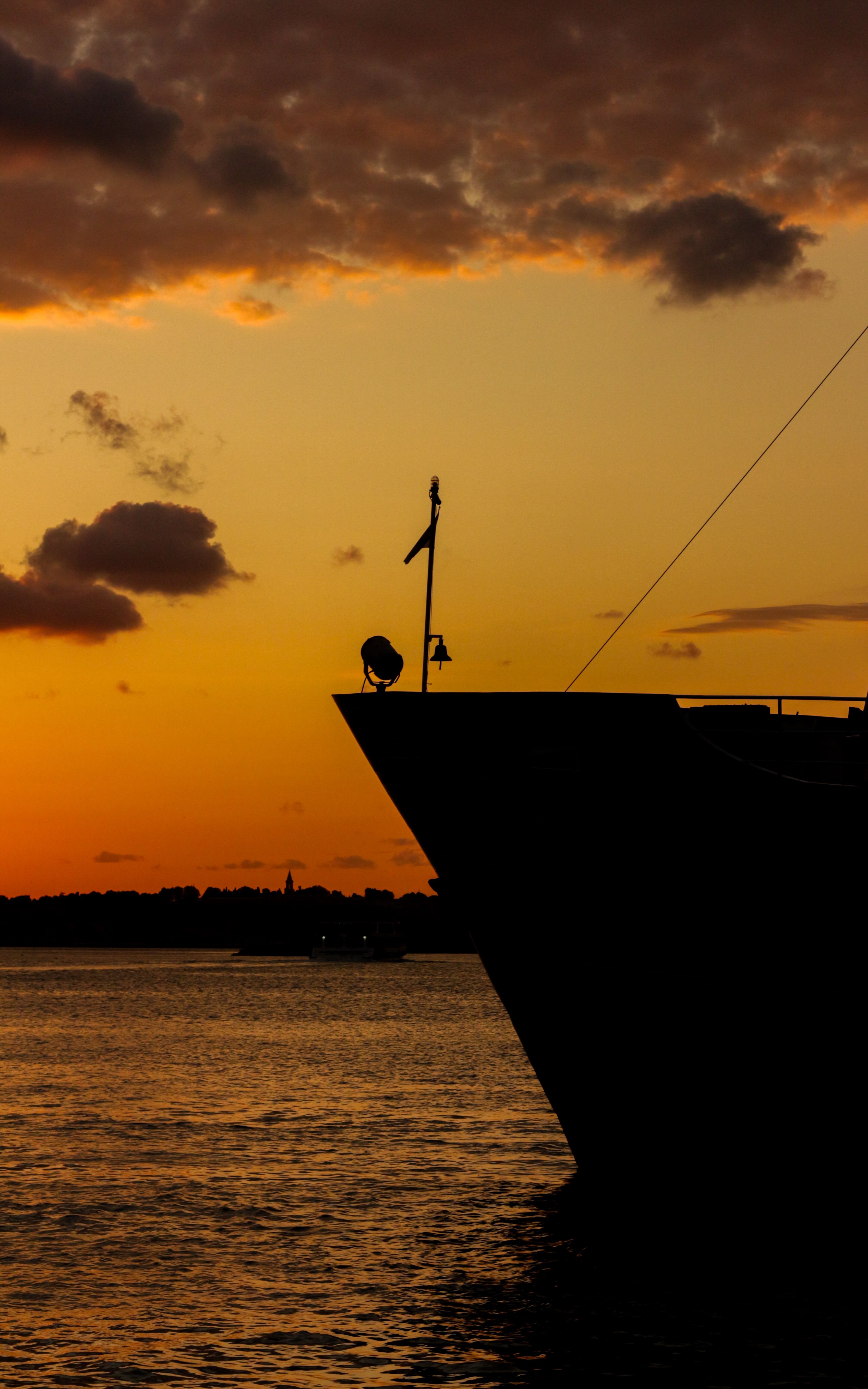 A boat is sailing in the water at sunset · Free Stock Photo