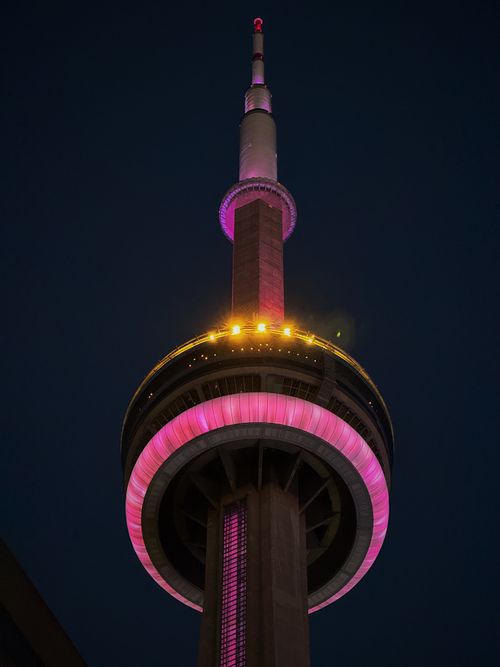 Free The CN Tower in Toronto lit up with vibrant pink colors against a dark night sky. Stock Photo