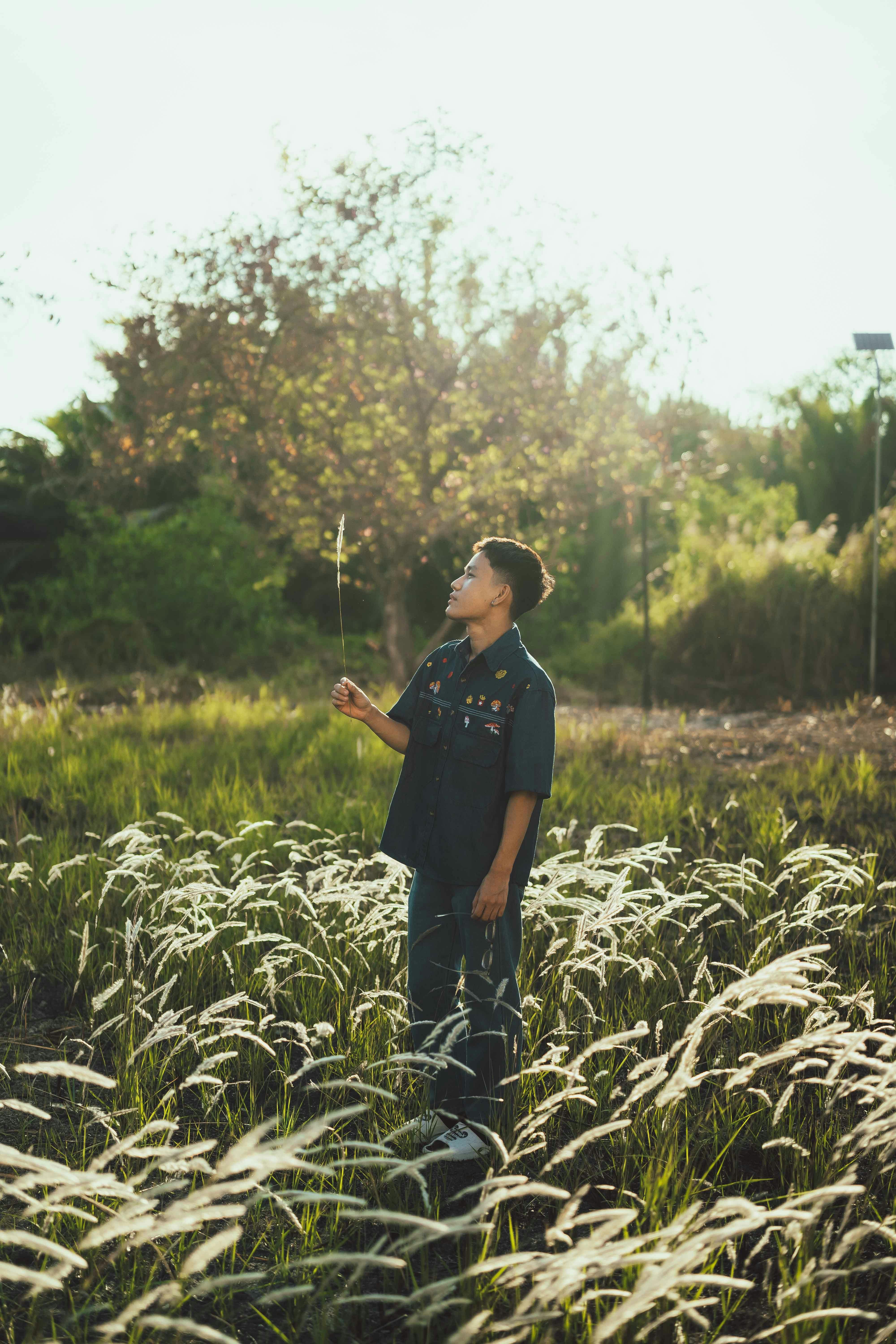 A man stands in a grassy field during daylight in Ho Chi Minh City, enjoying the serene surroundings.