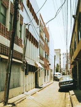A narrow city alley with old buildings and a vintage car, captured during daylight.