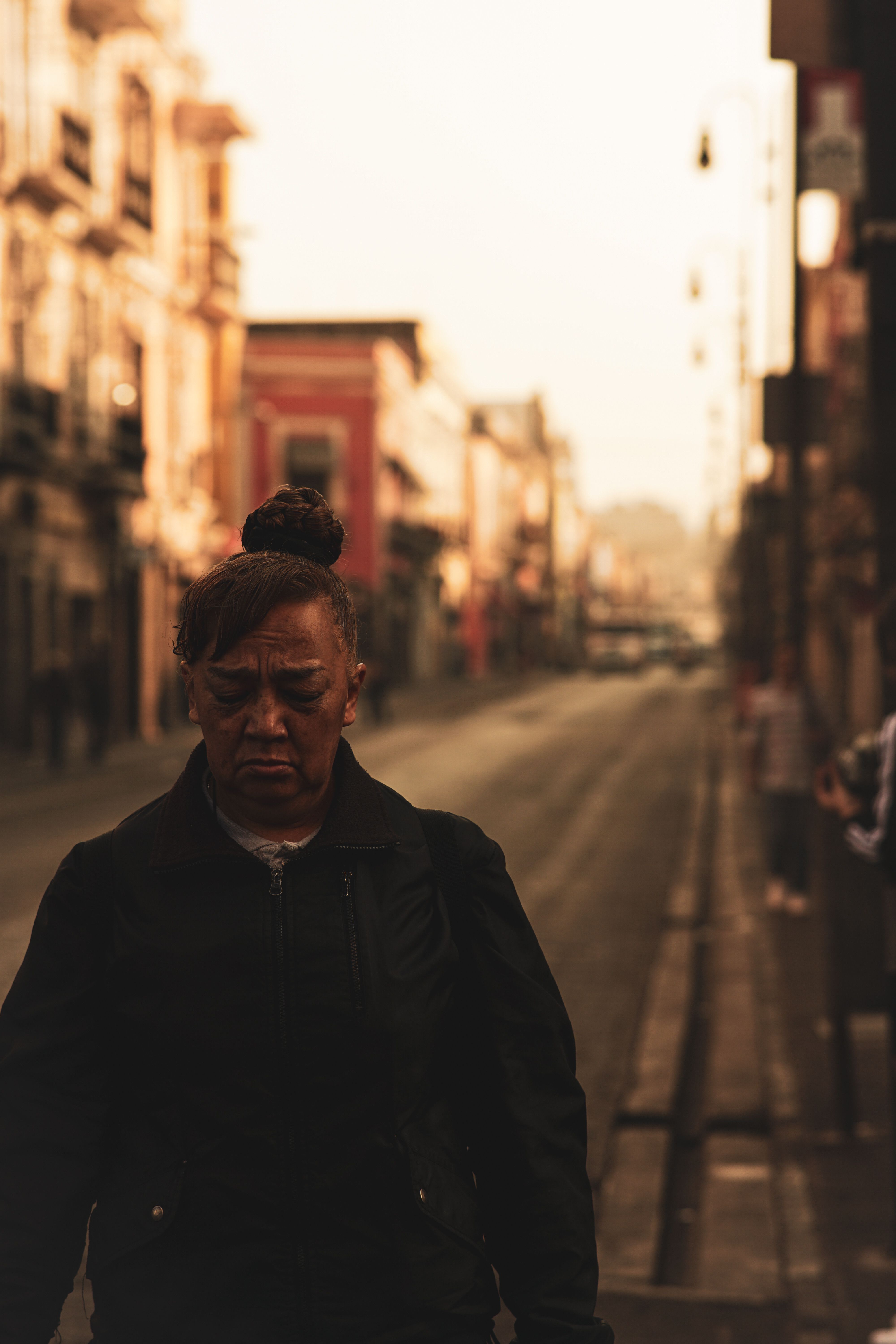 A pensive woman walking an urban street at sunset — photo by Emiliano Morales on Pexels