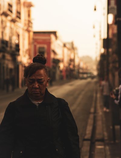A pensive woman walking an urban street at sunset — photo by Emiliano Morales on Pexels