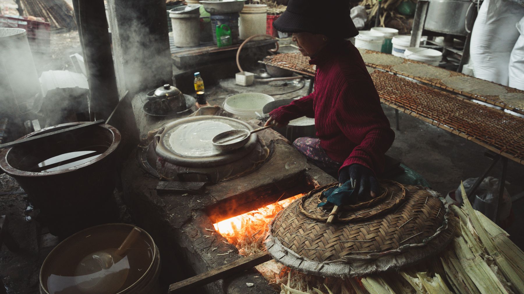 Artisan cooking with traditional methods over an open flame in a rustic kitchen.