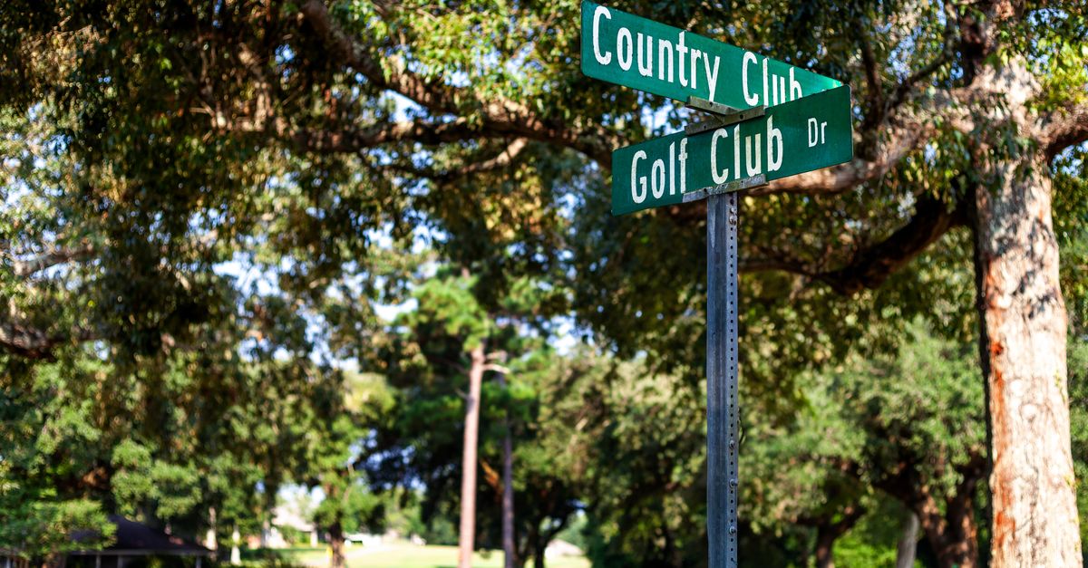 Street signs for Country Club and Golf Club Drive among lush greenery in Diamondhead, Mississippi.